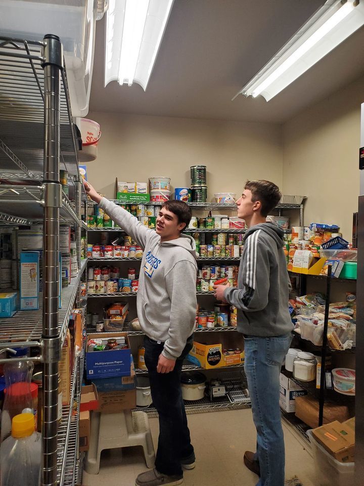 Two men putting groceries away in a storage room